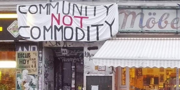 A shop front with home-made banner above with text "Community not commodity"