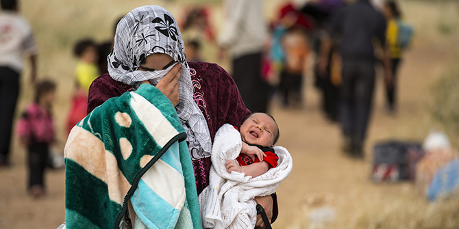 A young mother crosses the border from Syria and becomes a refugee. She carries her one-month-old son, Hamid. UNHCR / S. Rich / April 2013