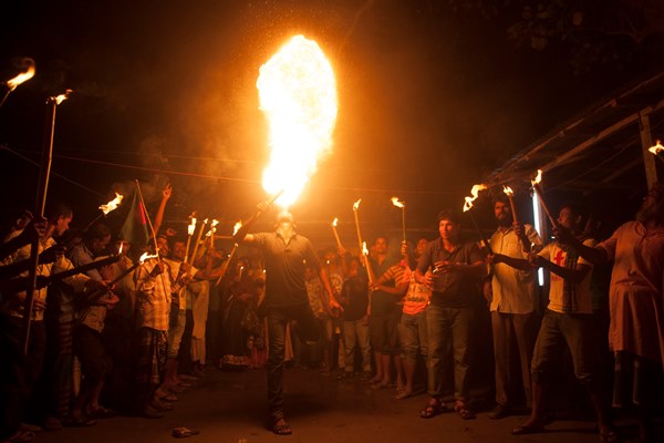 Former Indian enclave residence spits fire as they take part in a procession with torch at Dasiarchhara, Kurigram, Bangladesh, Aug 01, 2015.